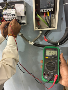 Electrician testing a home distribution panel with a multimeter